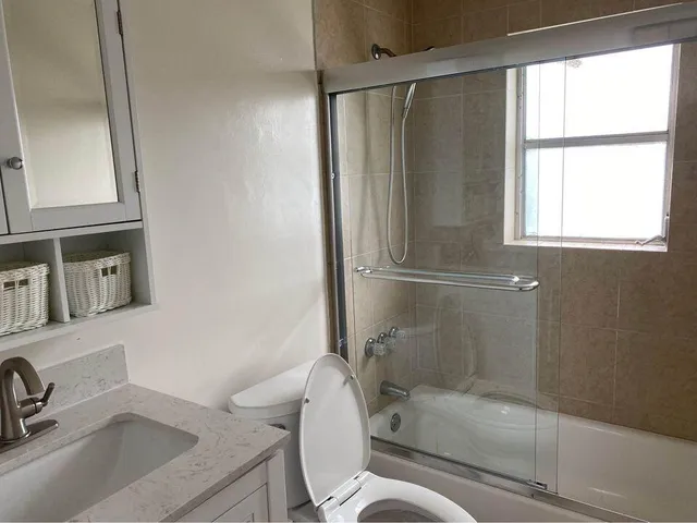 a bathroom with a granite countertop sink toilet and shower