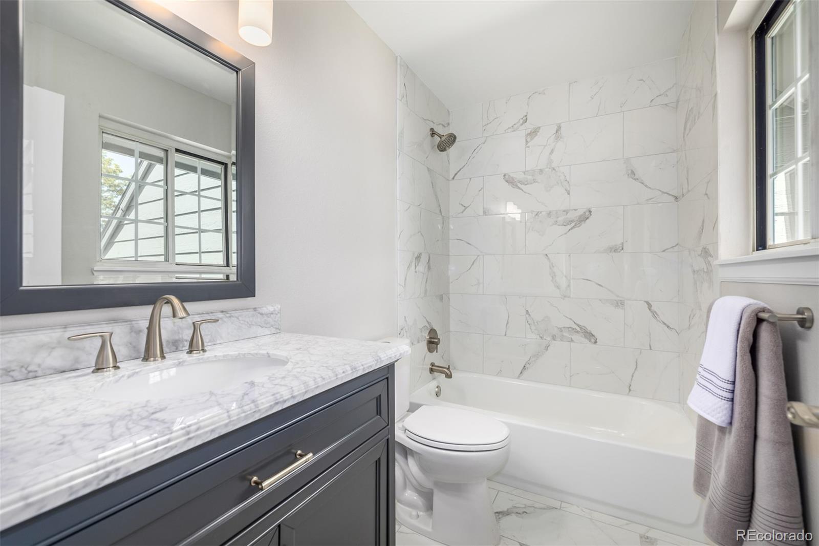 10401 West Red Mountain Road Littleton, CO 80127 - Photo 27 of 40 a bathroom with a granite countertop sink a toilet and bathtub