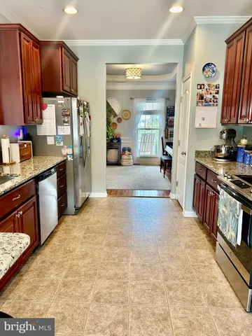 a kitchen with stainless steel appliances granite countertop a sink a stove top oven a dining table and chairs