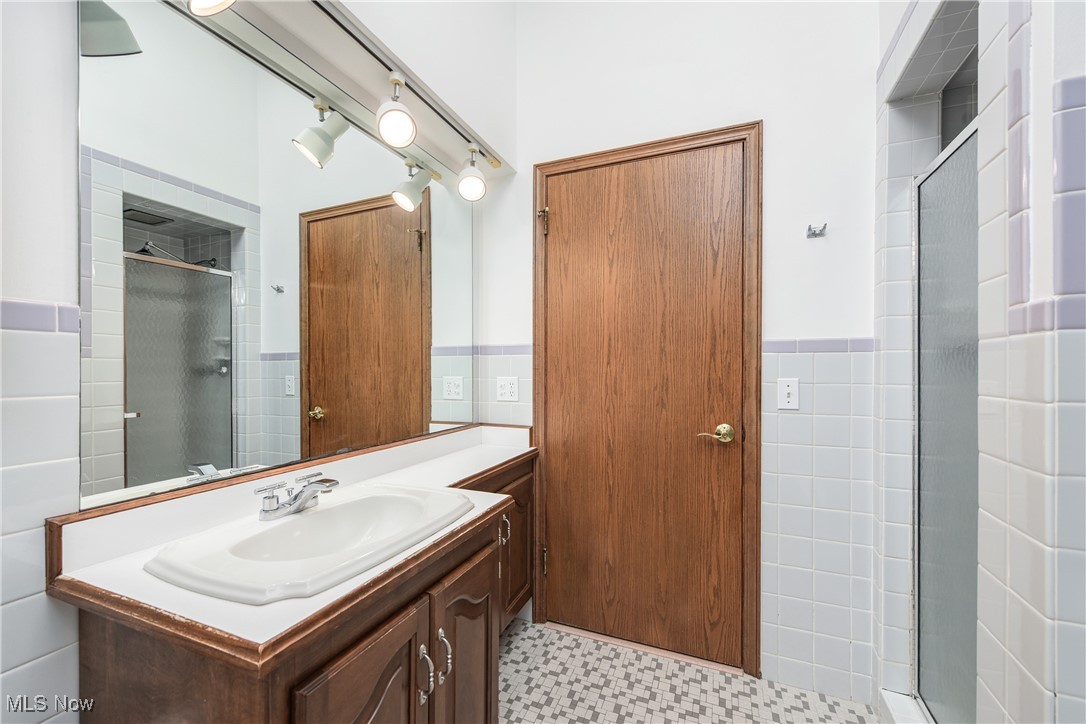 4712 Hillside Road Independence, OH 44131 - Photo 19 of 47 Full bath with tile walls, a shower stall, vanity, and wainscoting