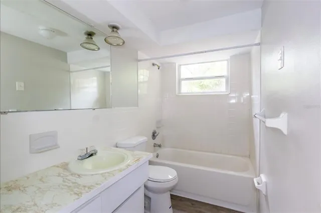 a bathroom with a granite countertop sink a toilet a mirror and bathtub