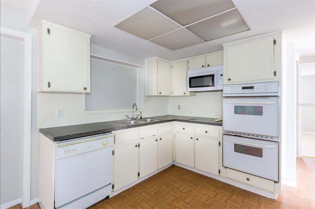 7735 Rottingham Road Port Richey, FL 34668 - Photo 10 of 24 a kitchen with granite countertop white cabinets and white appliances