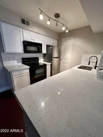 a kitchen with stainless steel appliances kitchen island granite countertop a sink dishwasher stove top oven and refrigerator