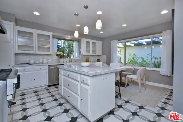 a kitchen with stainless steel appliances granite countertop a sink a stove a refrigerator cabinets and a large window