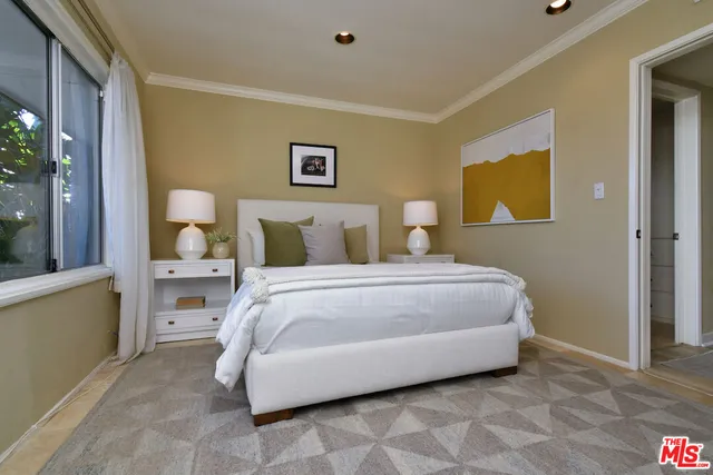 a bedroom with a bed a mirror on desk and chair