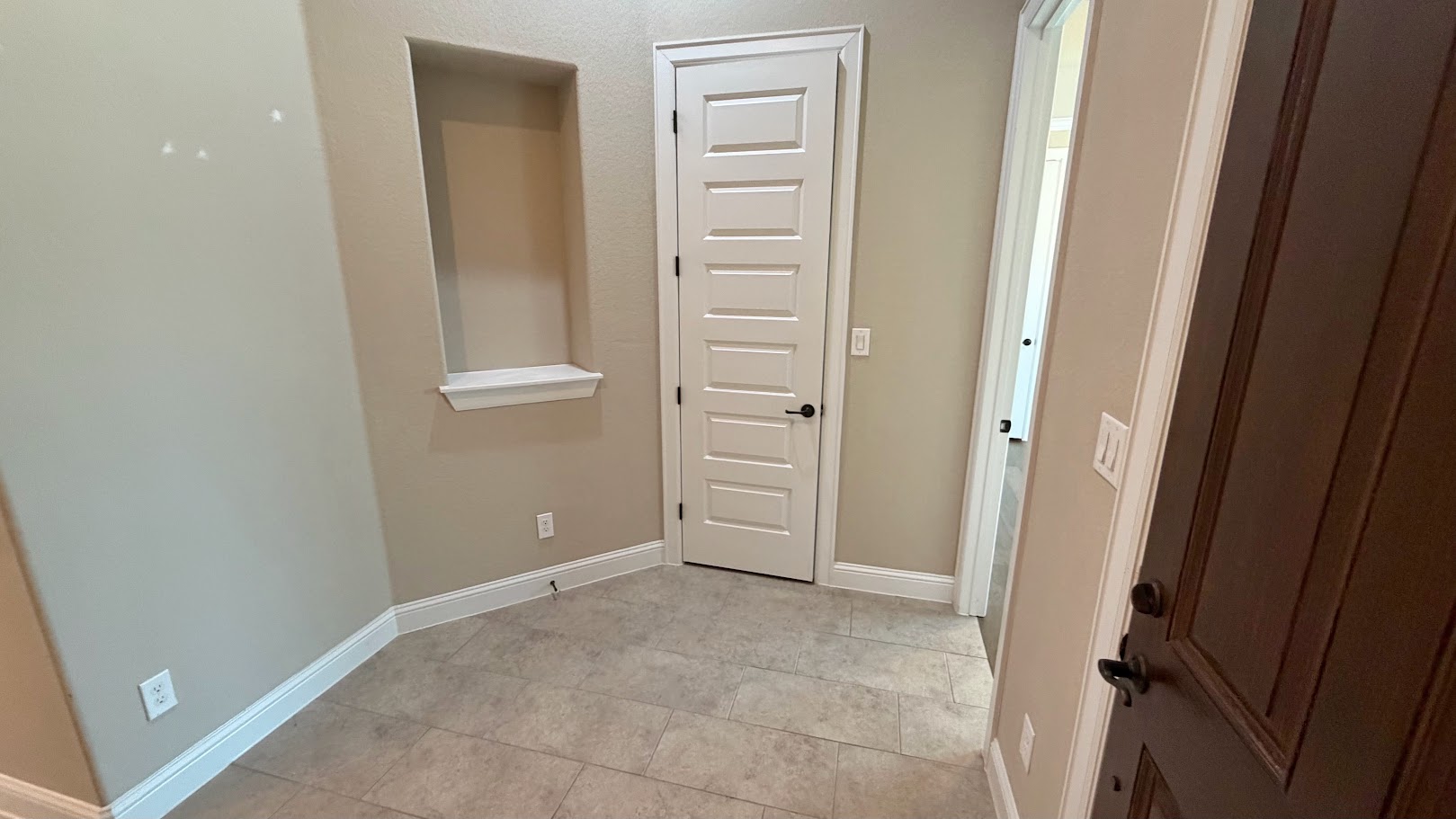 A well-proportioned entryway features durable tile flooring and a discreet wall niche.