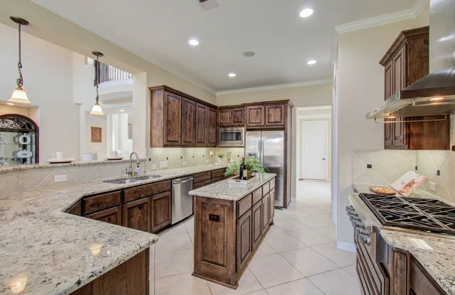a large kitchen with stainless steel appliances granite countertop a sink stove and refrigerator