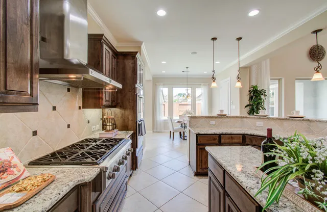a kitchen with stainless steel appliances granite countertop a stove a sink and a refrigerator