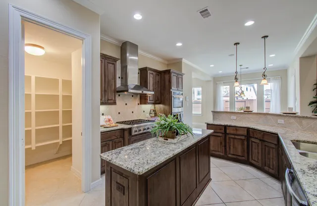 a kitchen with kitchen island granite countertop a sink and a stove