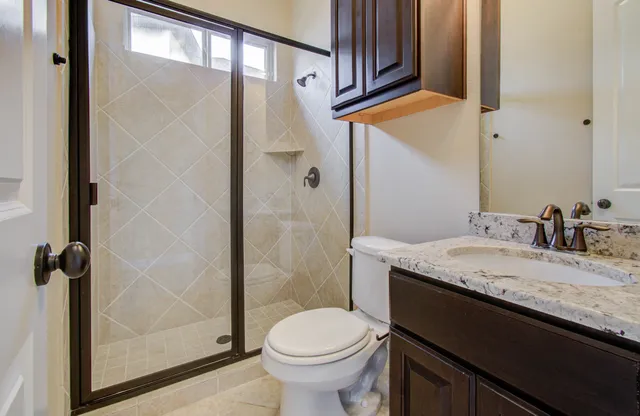 a bathroom with a granite countertop sink toilet and shower