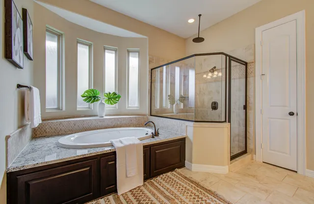 a spacious bathroom with a granite countertop sink a mirror and a shower
