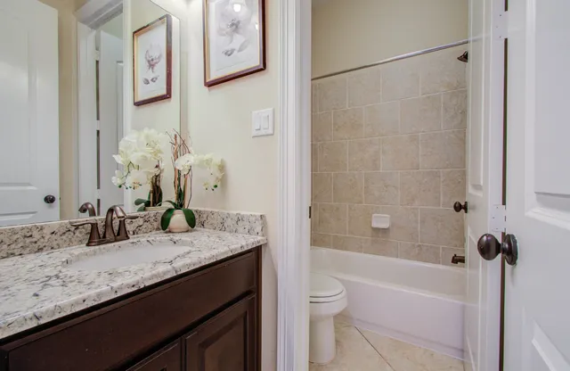 a bathroom with a granite countertop sink a toilet and bathtub