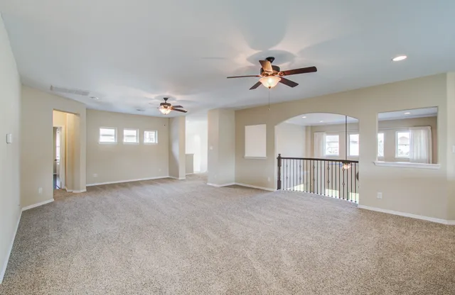 an empty room with windows and ceiling fan