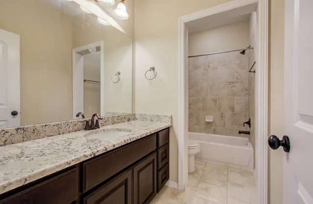 a bathroom with a granite countertop sink a toilet and shower
