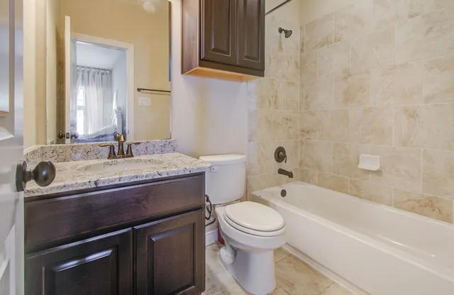 a bathroom with a granite countertop toilet sink and mirror