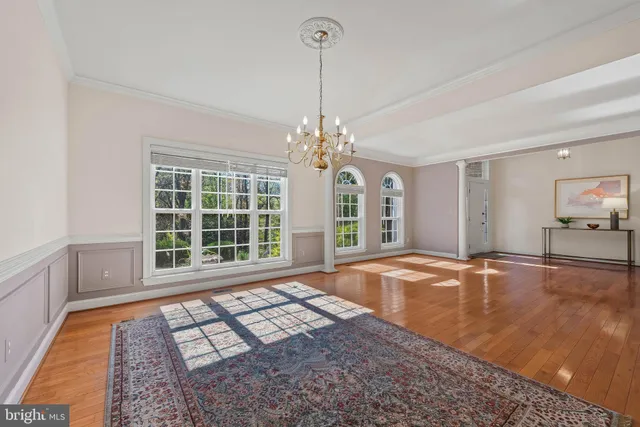 a view of an empty room with window and chandelier