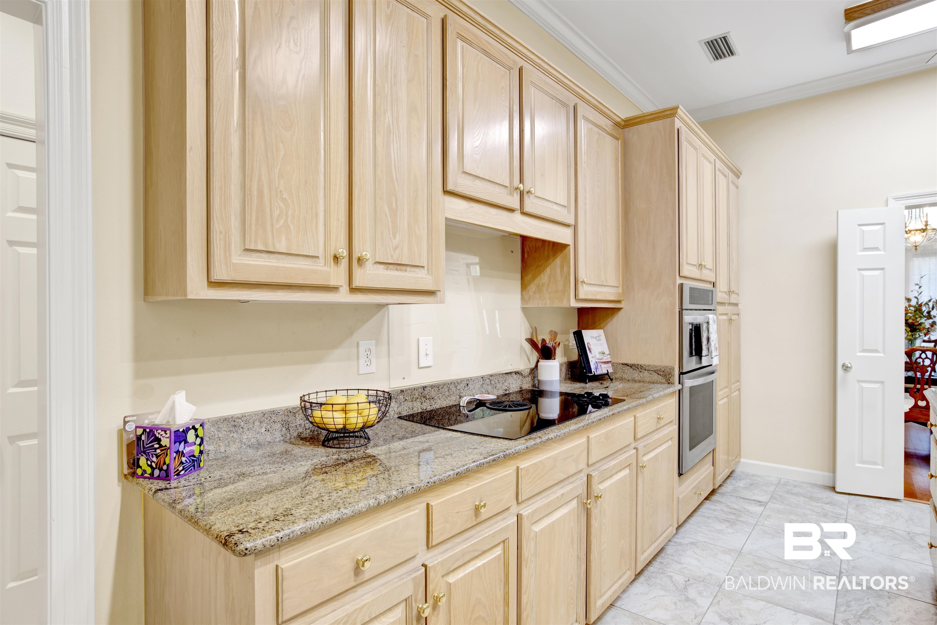 106 Old Mill Road Fairhope, AL 36532 - Photo 28 of 49 Kitchen with visible vents, black electric cooktop, ornamental molding, and light brown cabinets