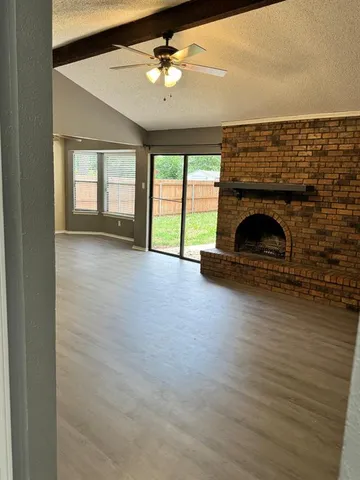 wooden floor fireplace and windows in an empty room