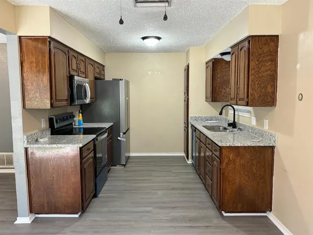 a kitchen with stainless steel appliances granite countertop a stove top oven a sink and a refrigerator