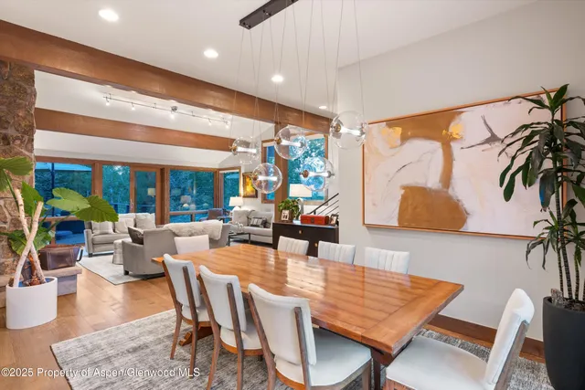 a view of a dining room with furniture one side kitchen view and wooden floor