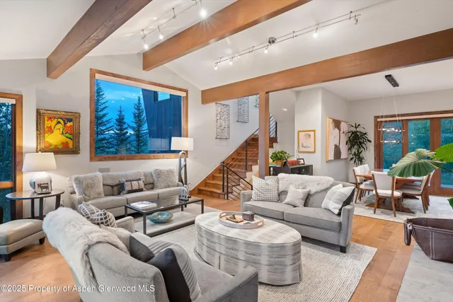 a living room with furniture kitchen view and a large window