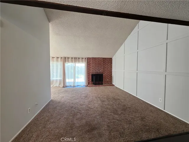 a view of an empty room with a fireplace and a window