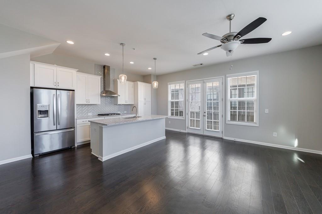 225 Britten Pass Alpharetta, GA 30009 - Photo 4 of 38 a kitchen with stainless steel appliances granite countertop a refrigerator a sink a stove and white cabinets with wooden floor
