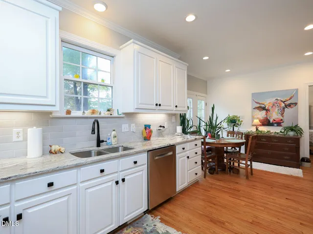 a kitchen with white cabinets and wooden floors