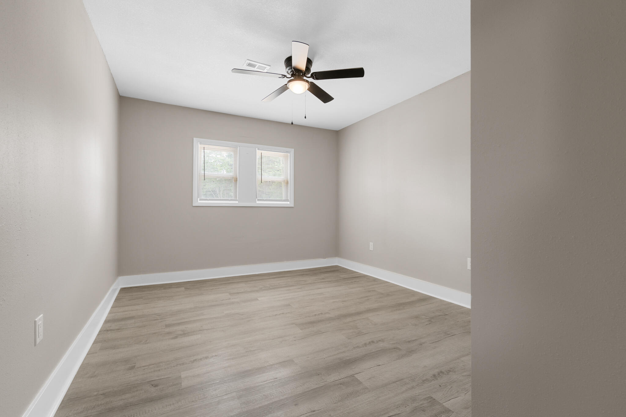 3437 Auburn Road Crestview, FL 32539 - Photo 15 of 26 an empty room with wooden floor ceiling fan and windows