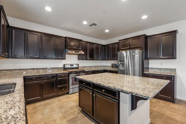 a kitchen with stainless steel appliances granite countertop a stove refrigerator sink and cabinets
