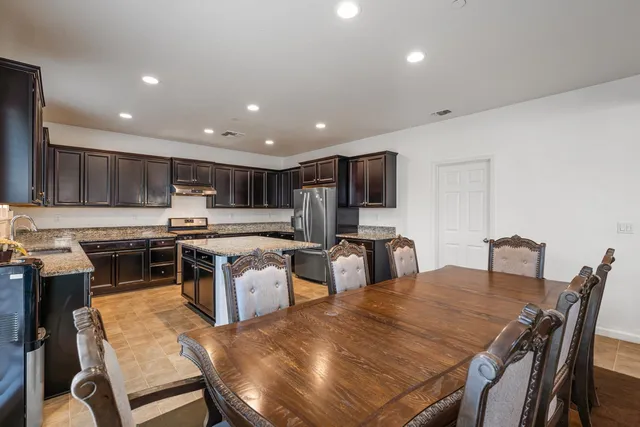 a kitchen with stainless steel appliances kitchen island granite countertop a stove a sink a dining table and chairs