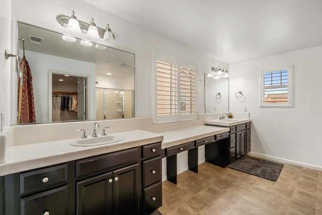 a spacious bathroom with a granite countertop sink a mirror and a bathtub