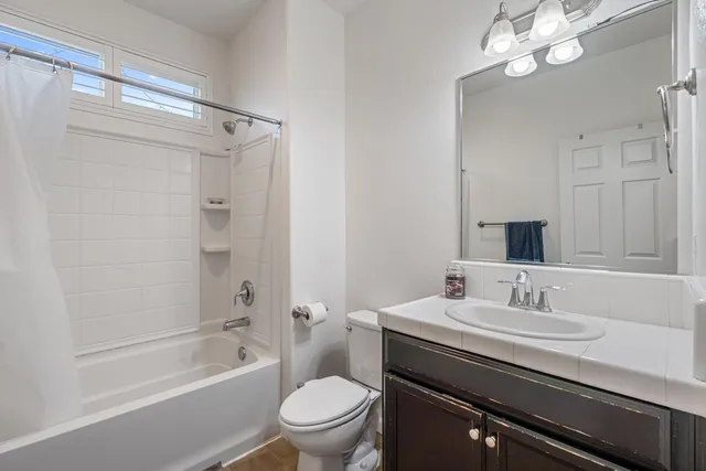 a bathroom with a sink a toilet a mirror a bathtub and shower