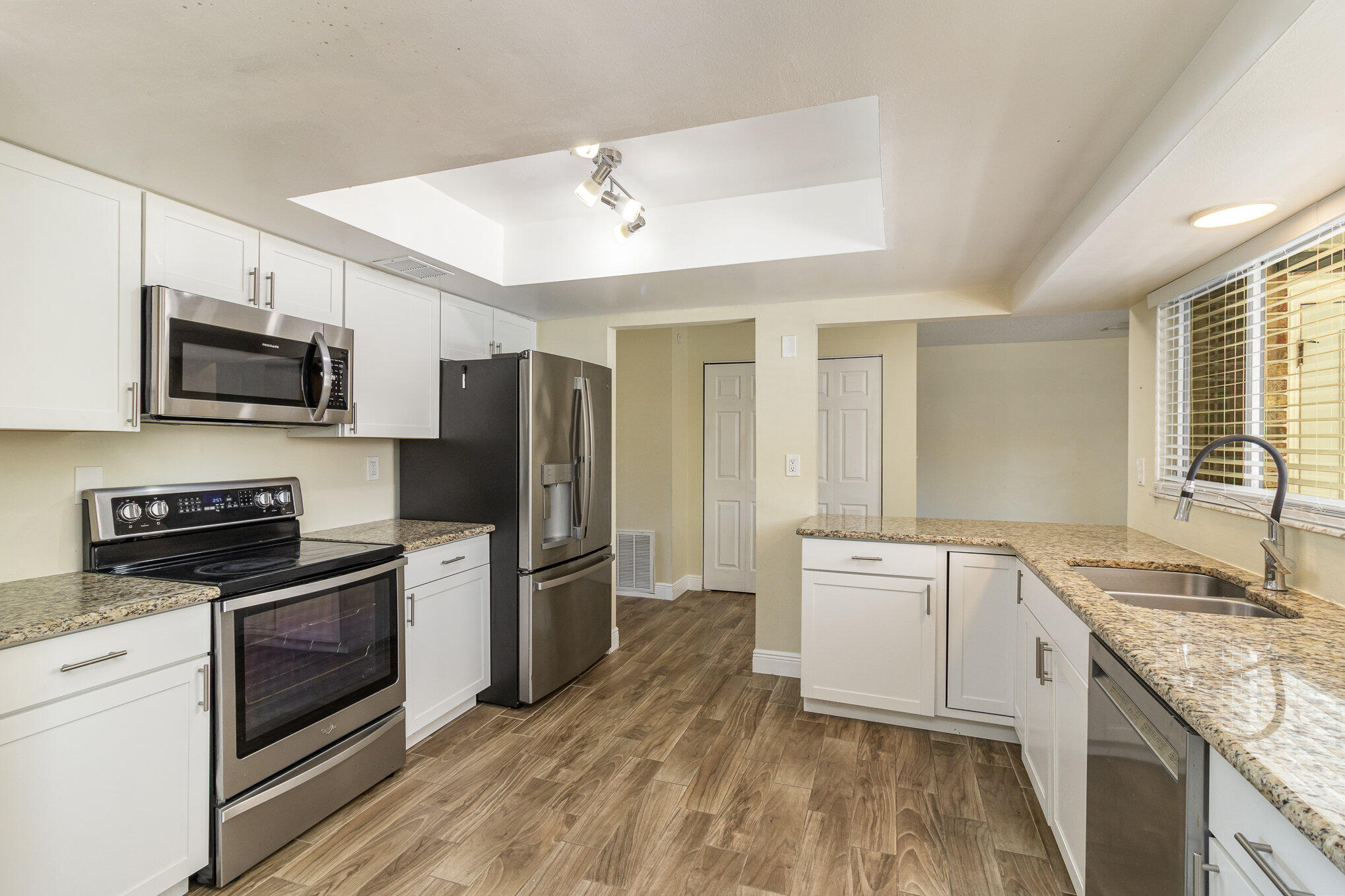 1294 Cimarron Circle Northeast Palm Bay, FL 32905 - Photo 17 of 45 a kitchen with stainless steel appliances granite countertop a stove top oven a sink dishwasher a refrigerator and a microwave oven with wooden floor