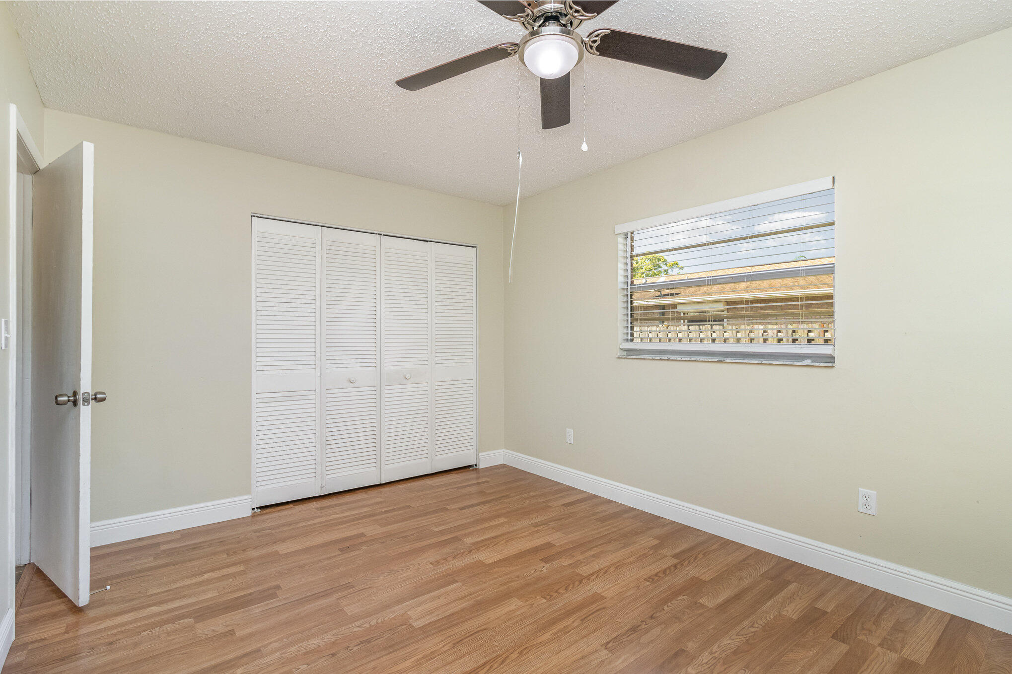 1294 Cimarron Circle Northeast Palm Bay, FL 32905 - Photo 31 of 45 an empty room with wooden floor fan and windows