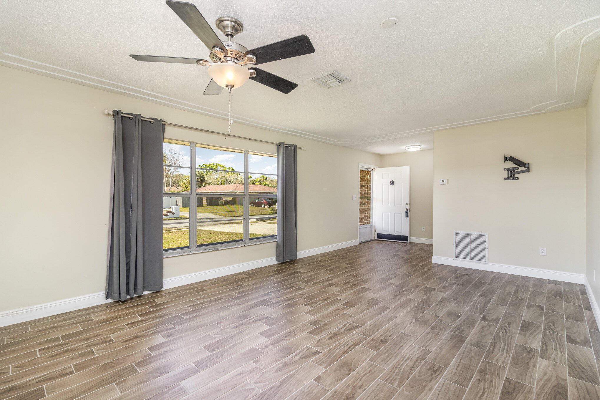 1294 Cimarron Circle Northeast Palm Bay, FL 32905 - Photo 5 of 45 an empty room with wooden floor and windows