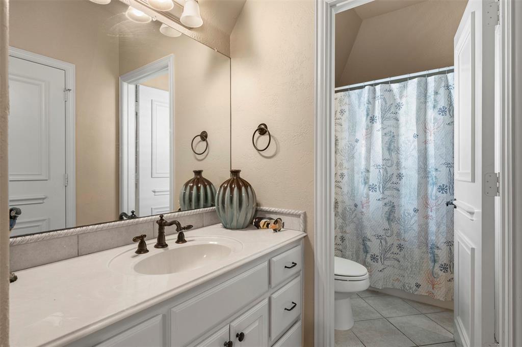 801 White Buffalo Lane Heath, TX 75032 - Photo 32 of 39 a bathroom with a granite countertop sink a toilet and a mirror