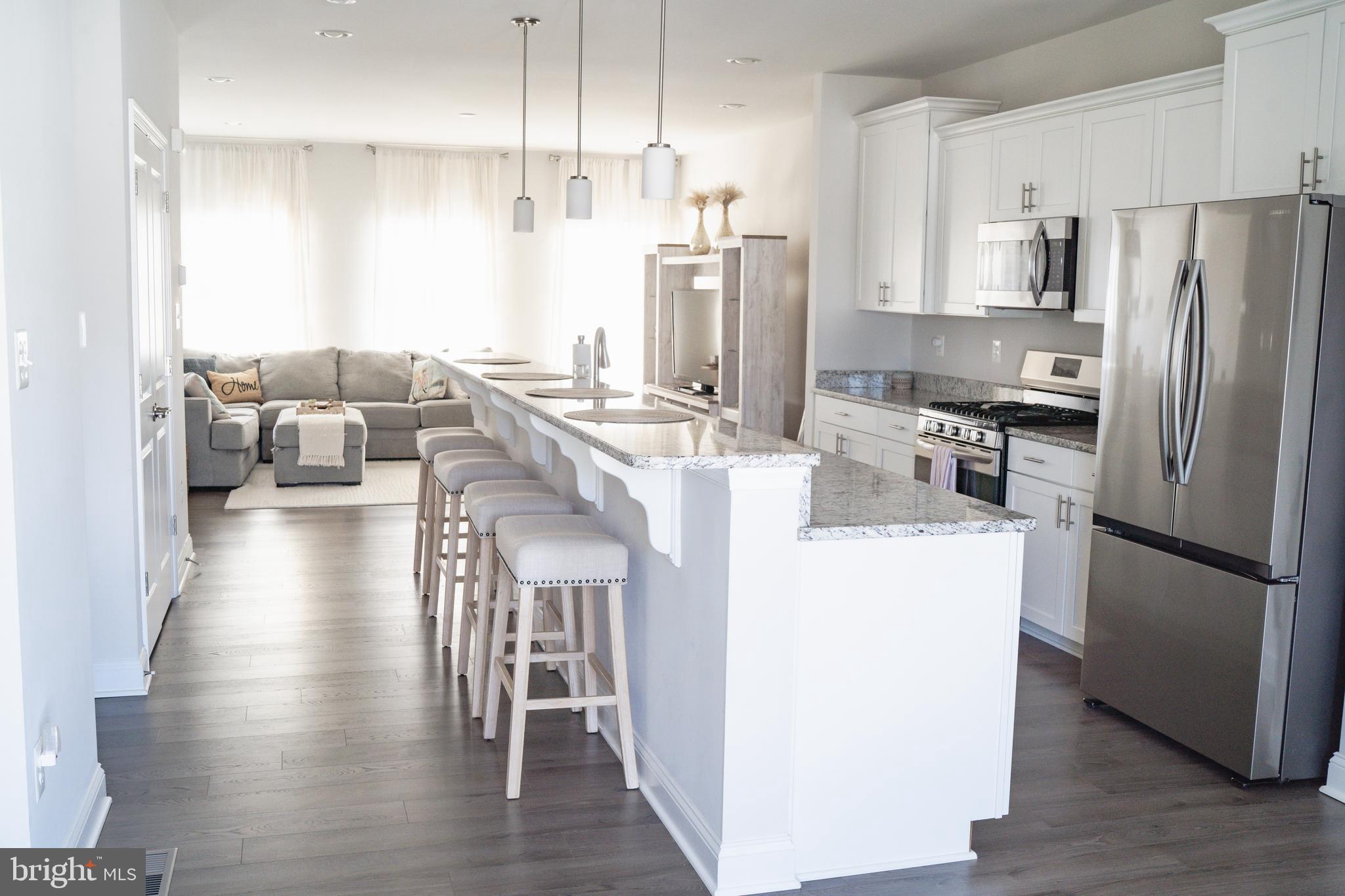36046 Auburn Way Millsboro, DE 19966 - Photo 4 of 56 a kitchen with kitchen island stainless steel appliances a refrigerator a stove a sink and white cabinets
