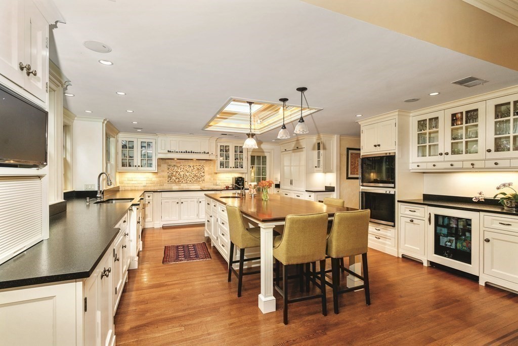 131 Oliver Road Newton, MA 02468 - Photo 11 of 41 a kitchen with stainless steel appliances granite countertop a stove top oven a sink dishwasher a dining table and chairs with wooden floor