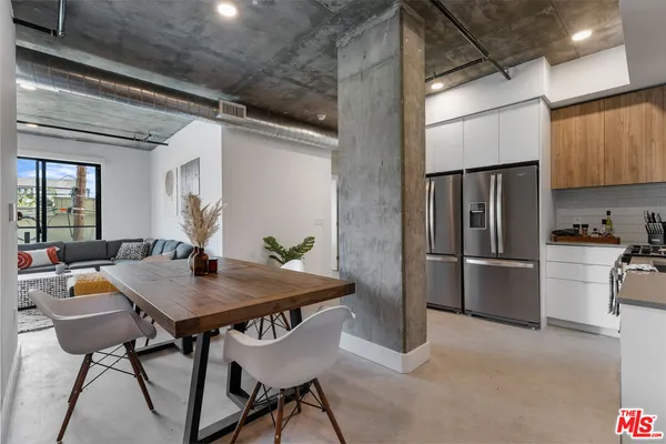 a kitchen with stainless steel appliances kitchen island a table and chairs in it
