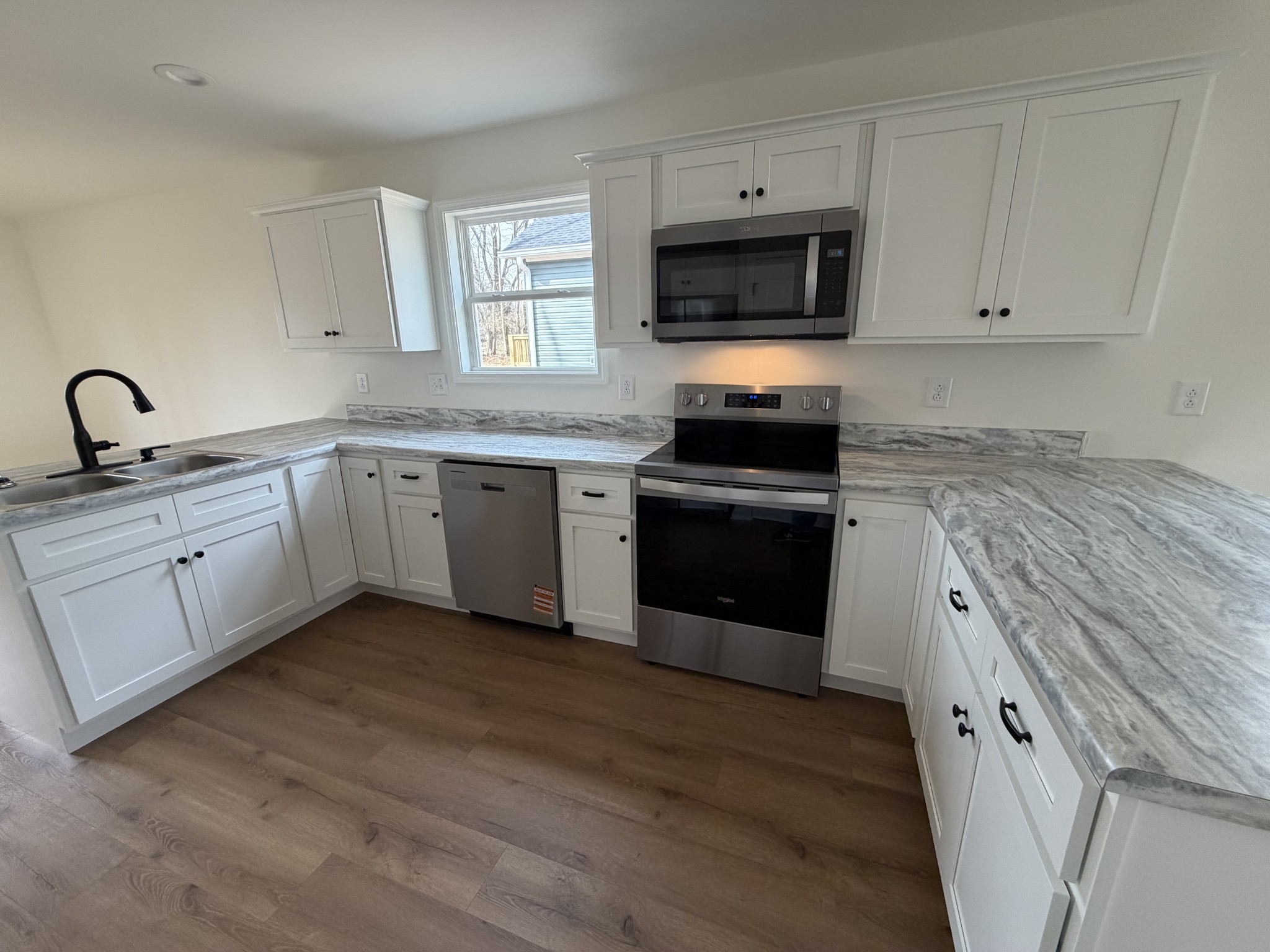 408 Church Street Portland, TN 37148 - Photo 3 of 11 a kitchen with stainless steel appliances granite countertop a stove top oven a sink and dishwasher with wooden floor