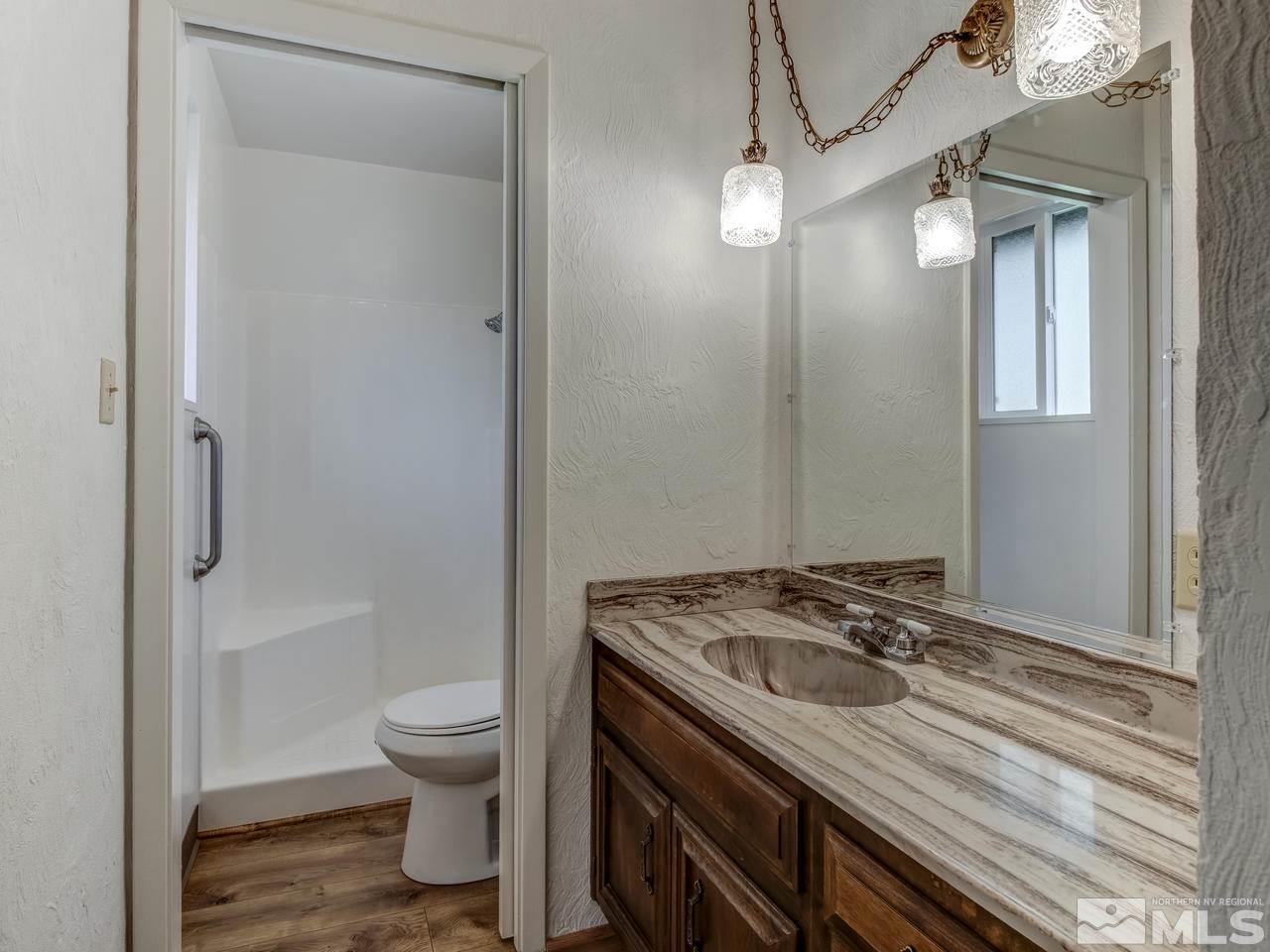 7465 Franktown Road Carson City, NV 89704 - Photo 17 of 25 a bathroom with a granite countertop sink toilet a mirror and shower