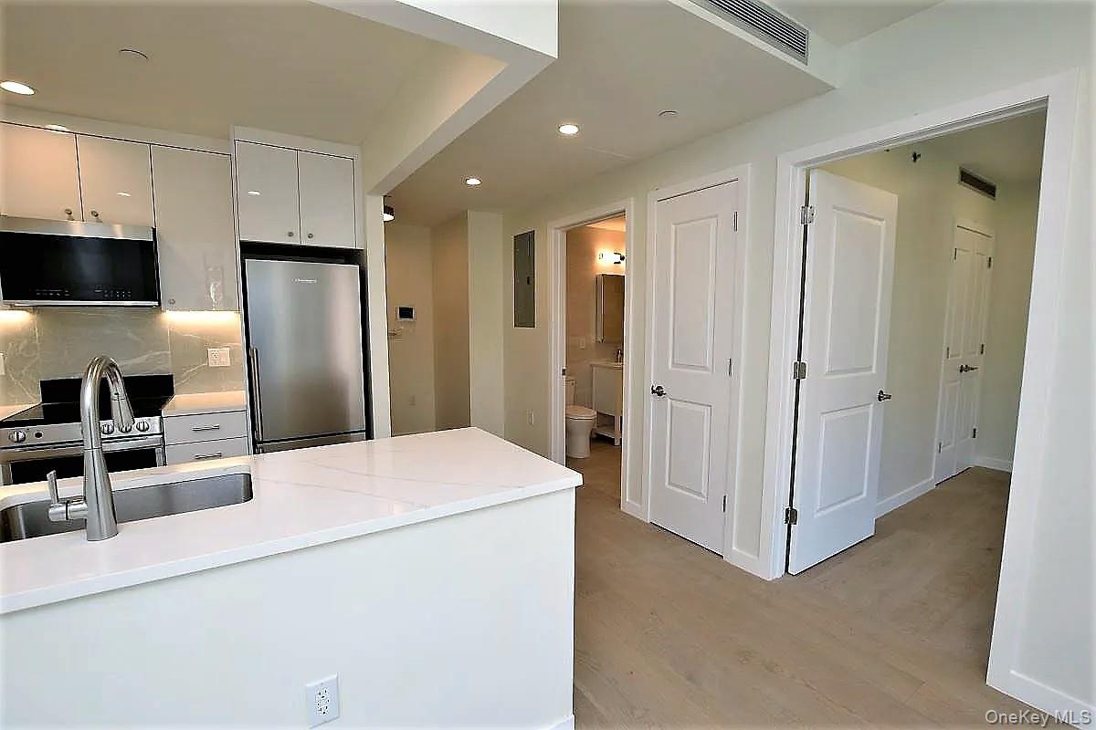 41-26 44th Street, Unit 3C Queens, NY 11104 - Photo 8 of 26 Kitchen with stainless steel appliances, recessed lighting, light wood-style flooring, tasteful backsplash, and light stone countertops