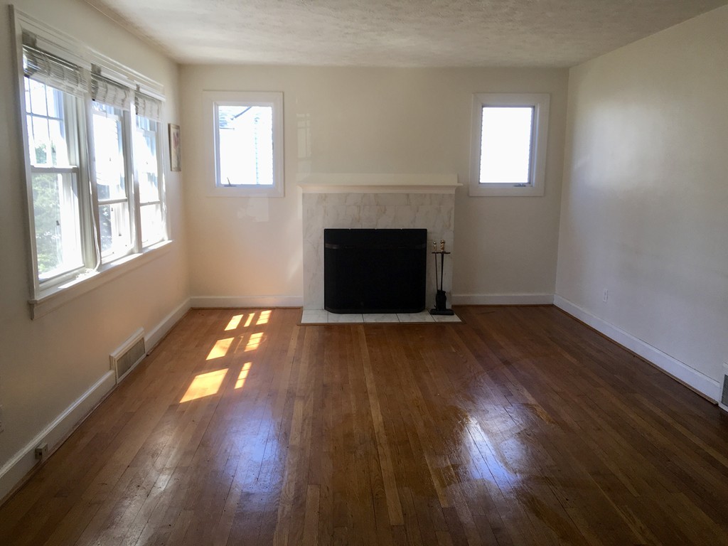133 Powell Avenue Springfield, MA 01118 - Photo 4 of 15 an empty room with wooden floor fireplace and windows