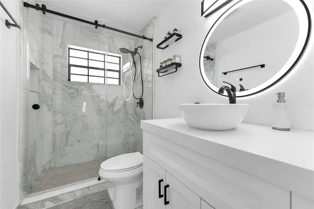 a bathroom with a sink a toilet and shower