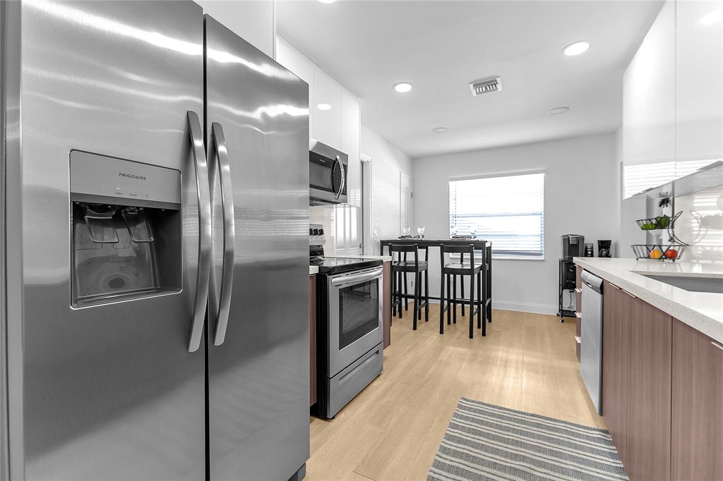 22718 Southwest 65th Terrace Boca Raton, FL 33428 - Photo 24 of 37 a kitchen with stainless steel appliances a refrigerator a stove a sink and a dining table with wooden floor