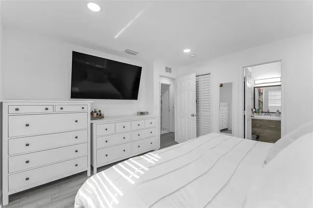 a bedroom with a bed a flat screen tv and a dresser