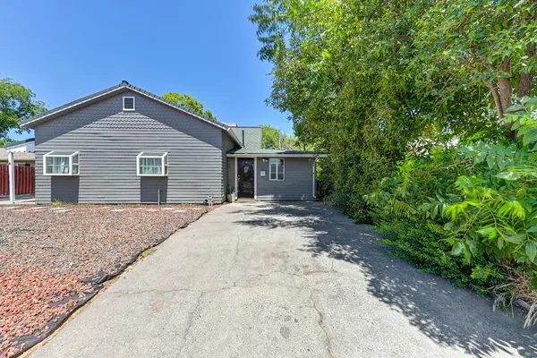 a view of a house with a yard and large tree