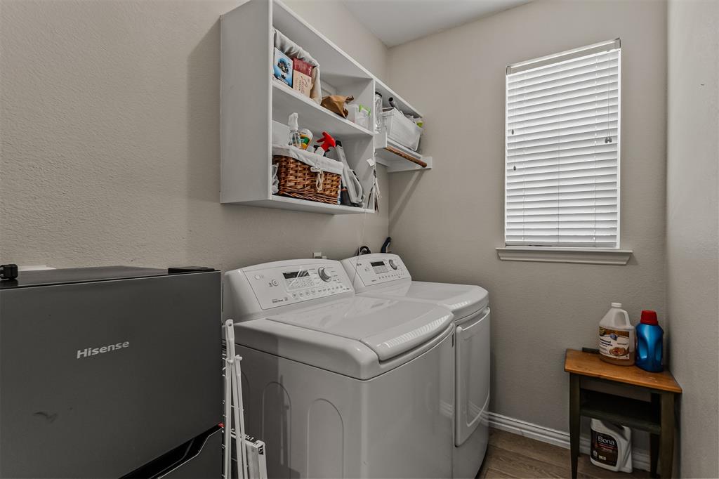 9301 Nottingham Court Rowlett, TX 75088 - Photo 26 of 39 Dedicated laundry area featuring a window with horizontal blinds, built-in white shelving, wood-finish flooring, and light neutral wall paint