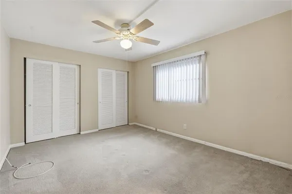 an empty room with a ceiling fan and a window